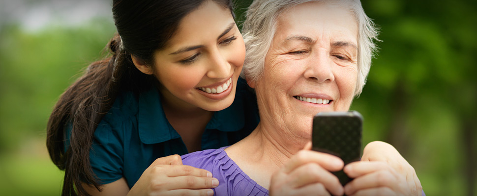 Young lady showing an older lady how to use a smart phone